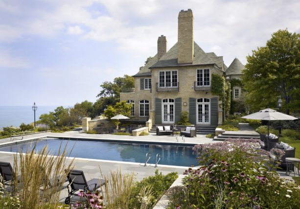 a traditional tan brick house with grey shutters