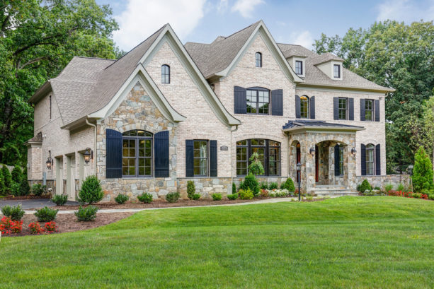 a traditional tan brick house with navy blue shutters
