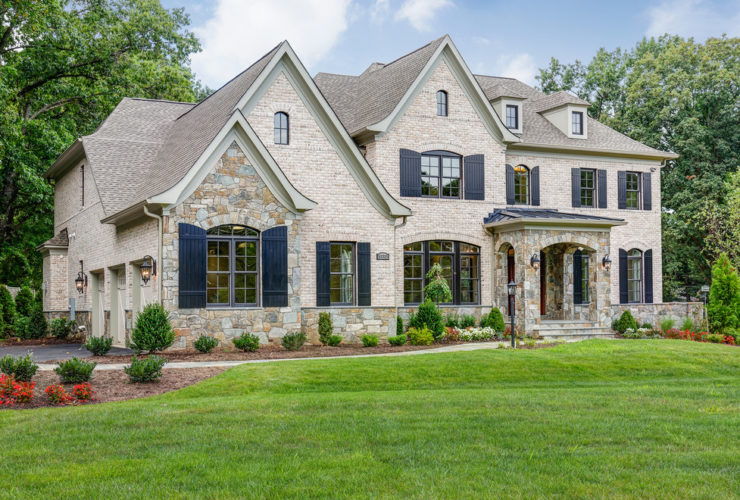 a traditional tan brick house with navy blue shutters