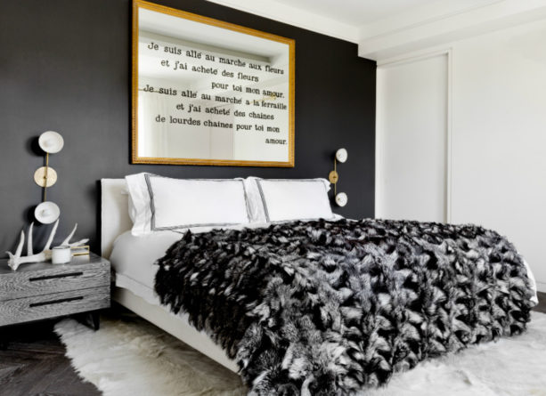a modern bedroom with black accent wall and gold-framed wall art