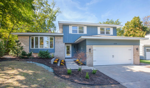 a slate blue house with white trim and tan brick detailing