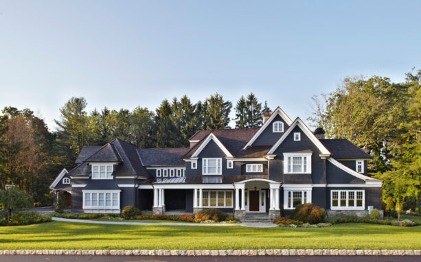 a traditional dark blue house with white trim and brown roof