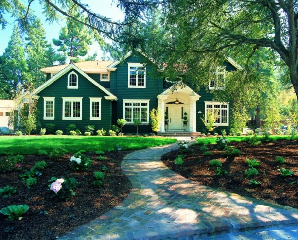 a traditional dark green house with medium tone brown roof