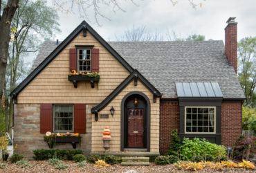 a traditional exterior with tan wall siding and red wood shutters