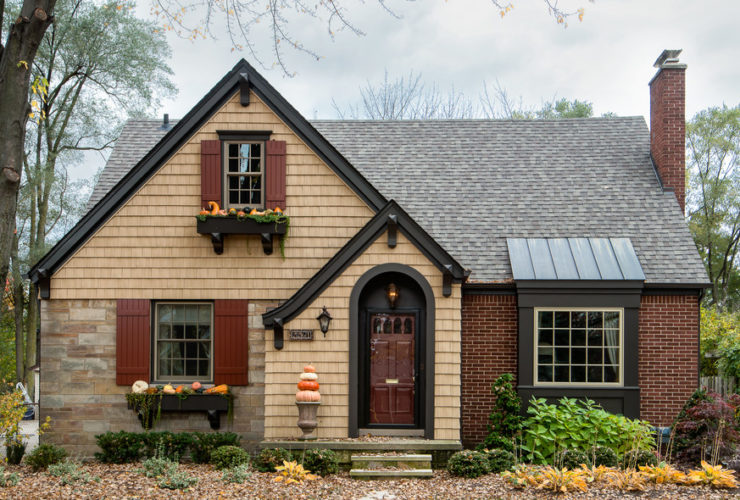 a traditional exterior with tan wall siding and red wood shutters