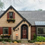 a traditional exterior with tan wall siding and red wood shutters