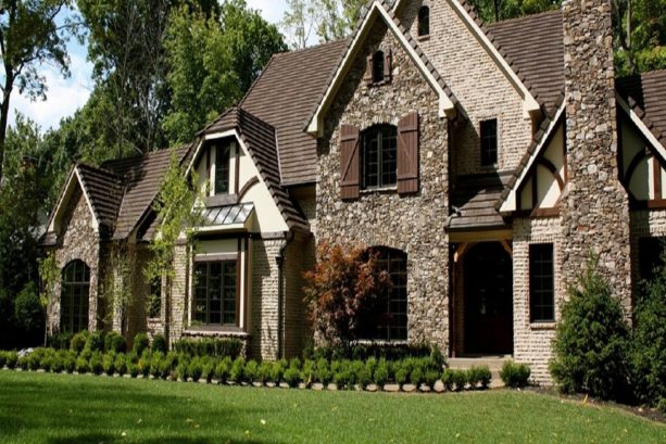 a traditional exterior with the mixture of brown roof, cream stucco, stone wall, and brick wall