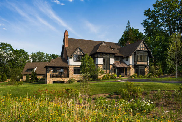 a traditional house with white paint, yellow stone wall, and brown roof
