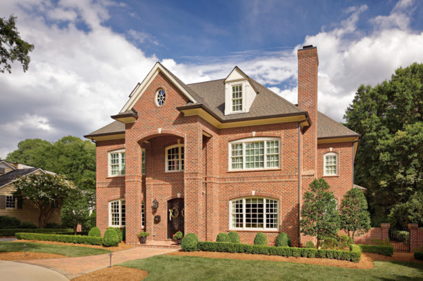 a traditional red brick house with medium brown roof