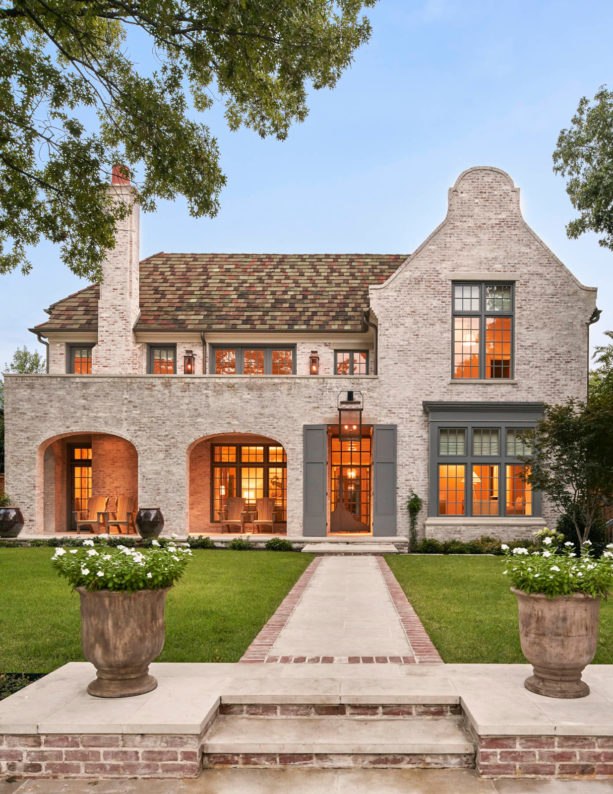a traditional tan brick house with multi-tone brown shingle roof