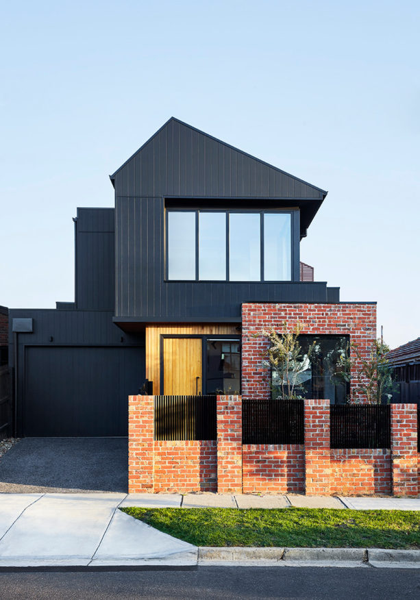 a contemporary house with black siding and red brick