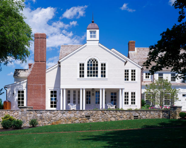 a traditional house with red brick chimney and white wall siding