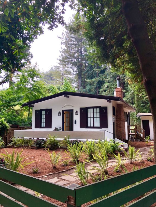 a white bungalow with yellow glass front door and black exterior trim