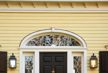 a black custom traditional front door with decorative transom and sidelights