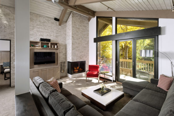 a red chair placed in front of a large glass window in a grey contemporary living room