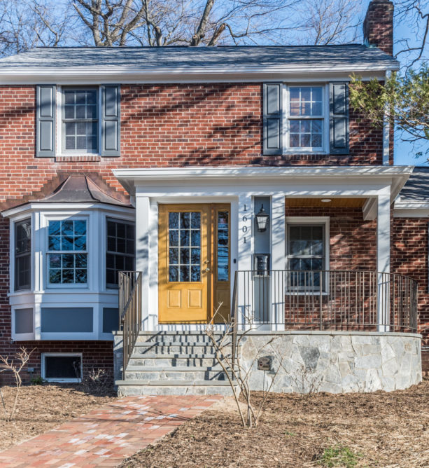 a red brick exterior with mustard yellow front door and white trim