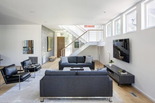 a TV mounted on the wall in front of windows in a higher position