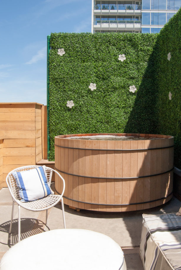 a beautiful screen created from faux hedge plant panels to add privacy to a hot tub
