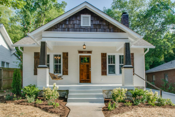 a craftsman house with painted white brick and stained wood combination