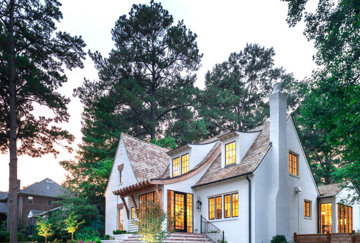 white-painted brick home with unique single gable roof and red brick accents