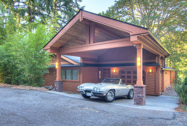 sizeable arts and crafts carport in front of a wooden siding garage