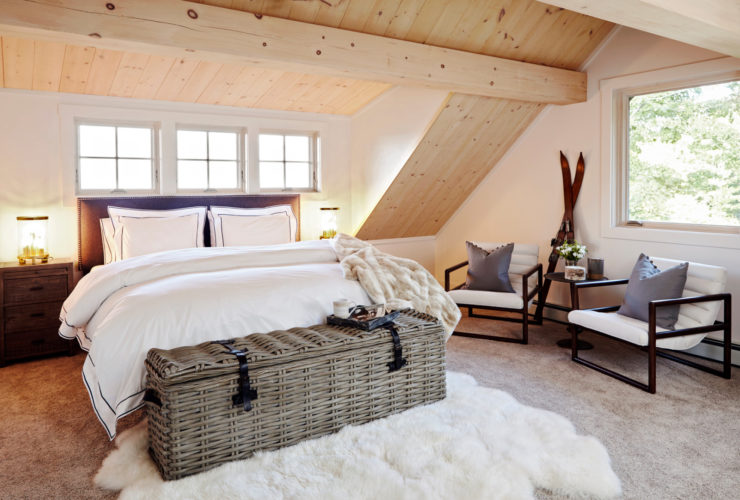 rustic attic bedroom with vaulted ceiling and slanted walls in a natural wood finish