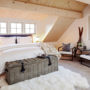 rustic attic bedroom with vaulted ceiling and slanted walls in a natural wood finish