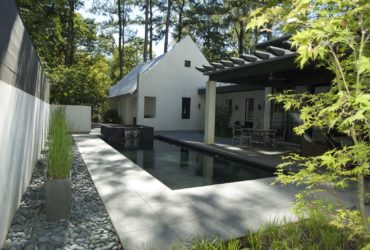 a minimalist backyard with stamped concrete around a rectangular pool