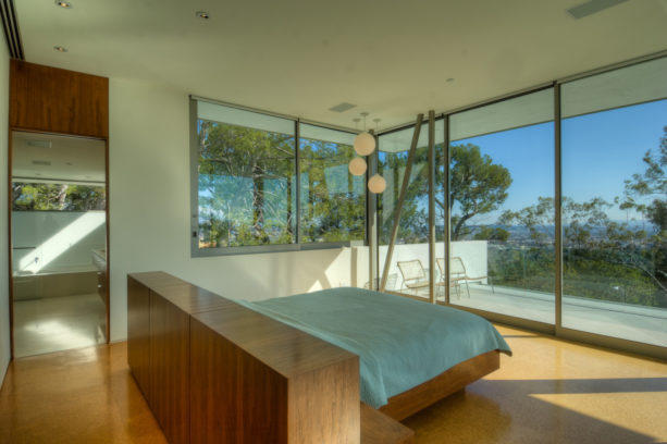 standard double bed with wooden headboard in the middle of a minimalist room