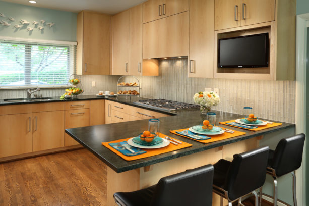 u-shaped trendy kitchen with medium tone wood floor and a peninsula with black soapstone countertops