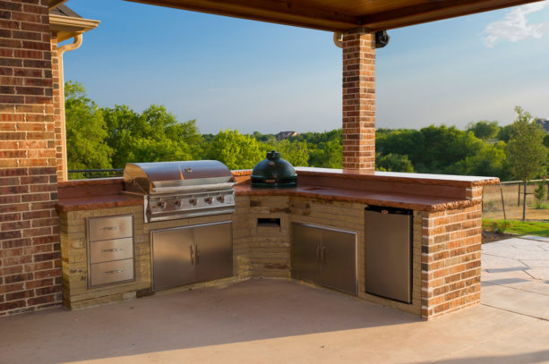 transitional covered l-shaped outdoor kitchen with exposed red brick walls