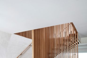 wooden staircase in an open and l-shaped design with a vertical wood slat wall