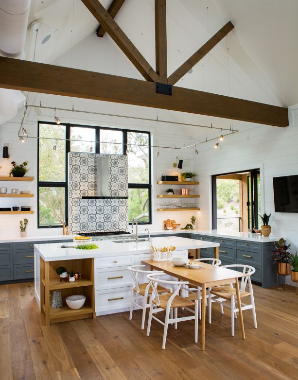 open concept kitchen with deep gray cabinets and sleek white countertops along with multicolored backsplash