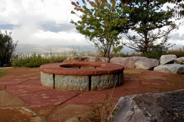 rustic backyard stone landscaping with a fire pit made of two types of stones