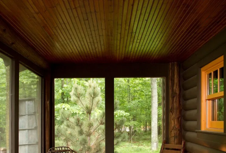 screened-in log cabin porch with a roof extension and decking