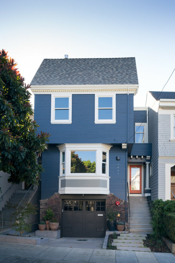white bay window exterior with gray panel against the blue wall