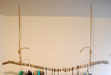 rustic styled hanging clothes rack from the ceiling made of a solid branch