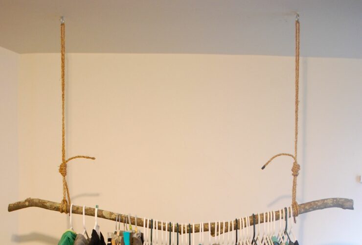 rustic styled hanging clothes rack from the ceiling made of a solid branch
