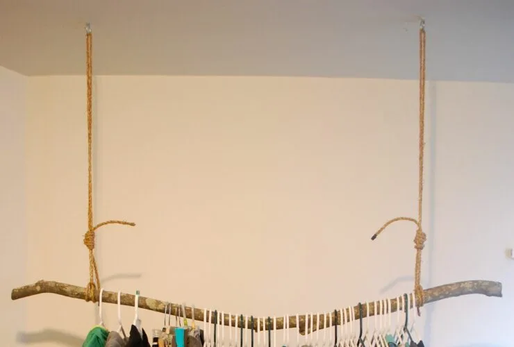 rustic styled hanging clothes rack from the ceiling made of a solid branch
